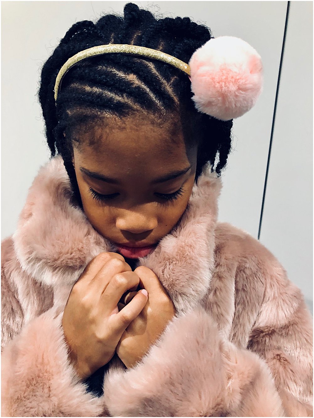 Little black girl holding on to a faux fur pink coat
