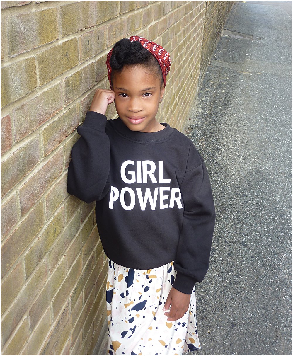 Little black girl wearing enpowering Girl Power slogan sweater from a collaboration with Lux and Black and Mini Edit