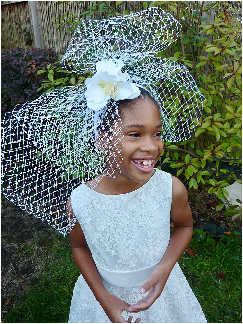 Little black girl smiling at wearing a gorgeous lace party dress by Little Bevan and head band by Clea Broad