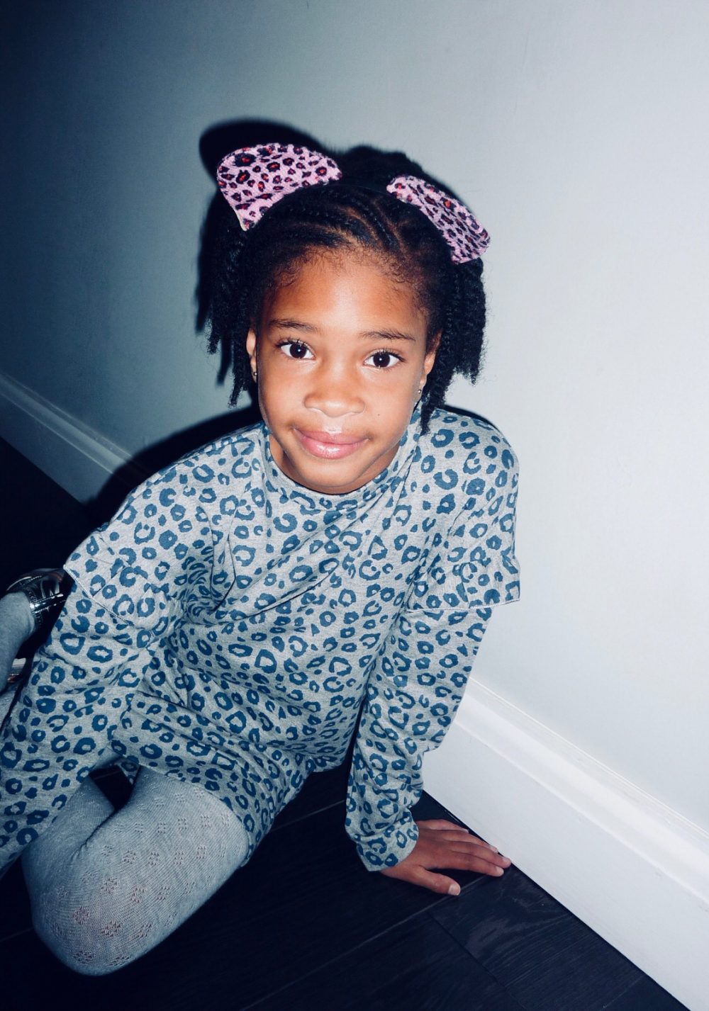 Little black girl in a blue coloured leopard print dress and pink headband.print